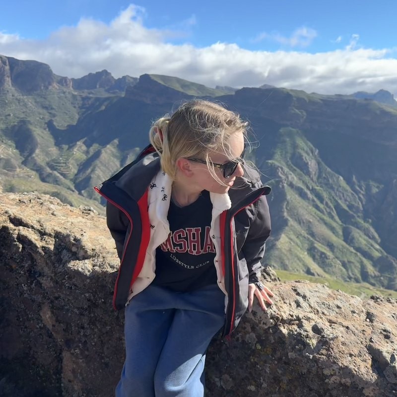 Anna sitting on a rock with mountains behind her